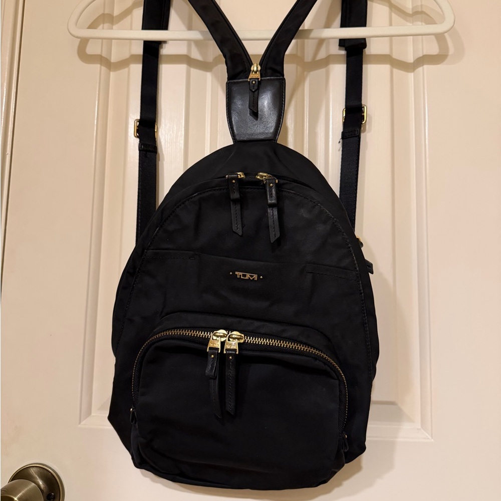Tumi women’s black nylon and leather backpack with gold hardware.